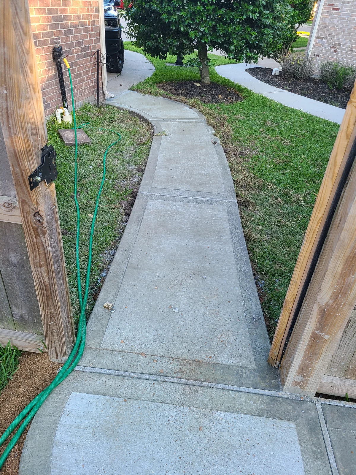 Curved residential concrete walkway beside a brick home