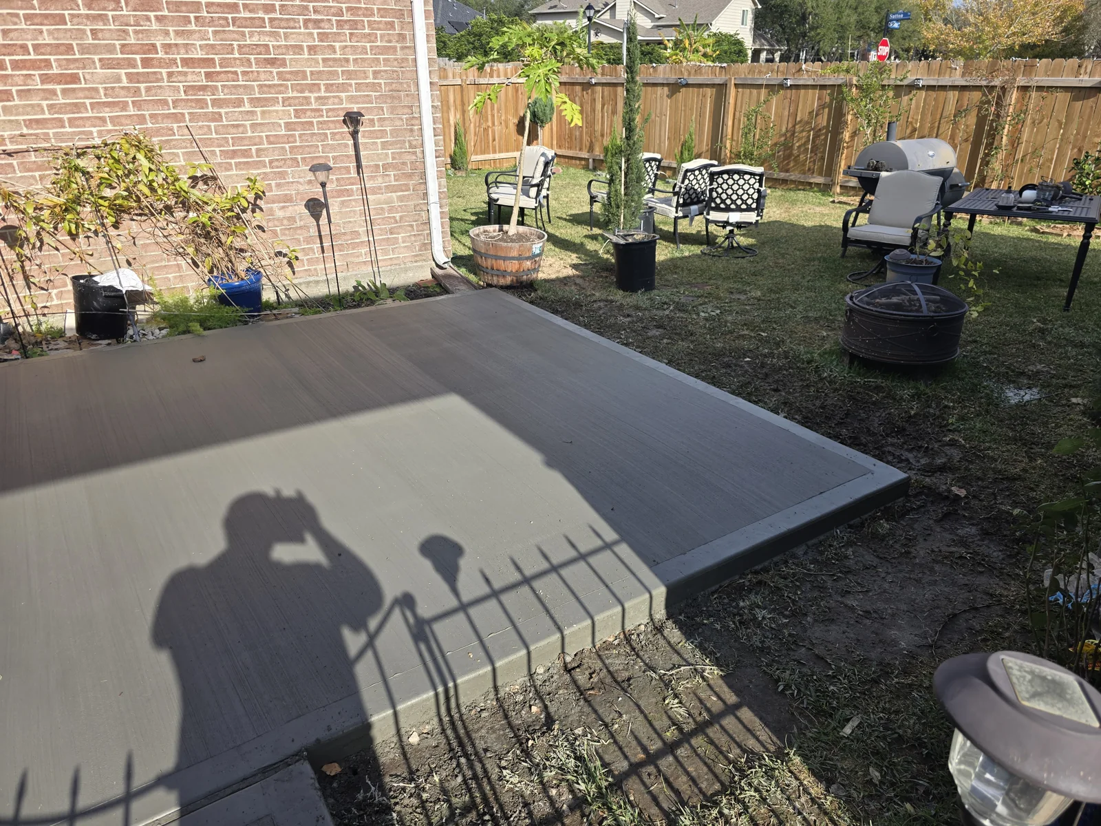 Fresh broom-finished backyard concrete patio beside a brick home, photographed December 2025