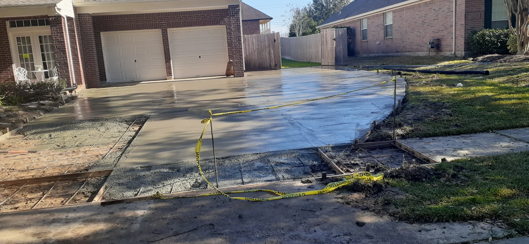 Fresh concrete driveway in front of a brick home
