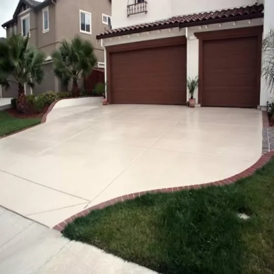 United Concrete curved concrete driveway with a red brick border in front of a two-door garage